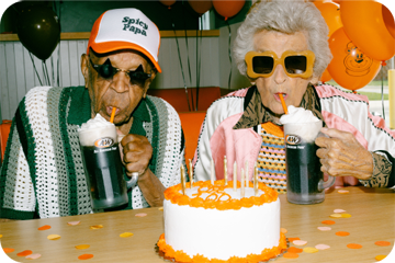 Two elderly people drinking root beer floats