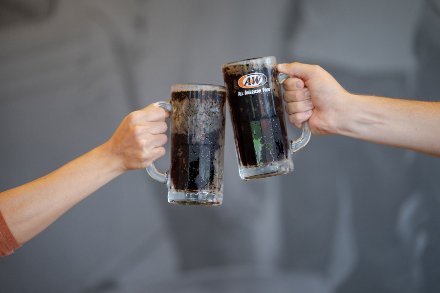 Two people toasting with mugs of A&W Root Beer