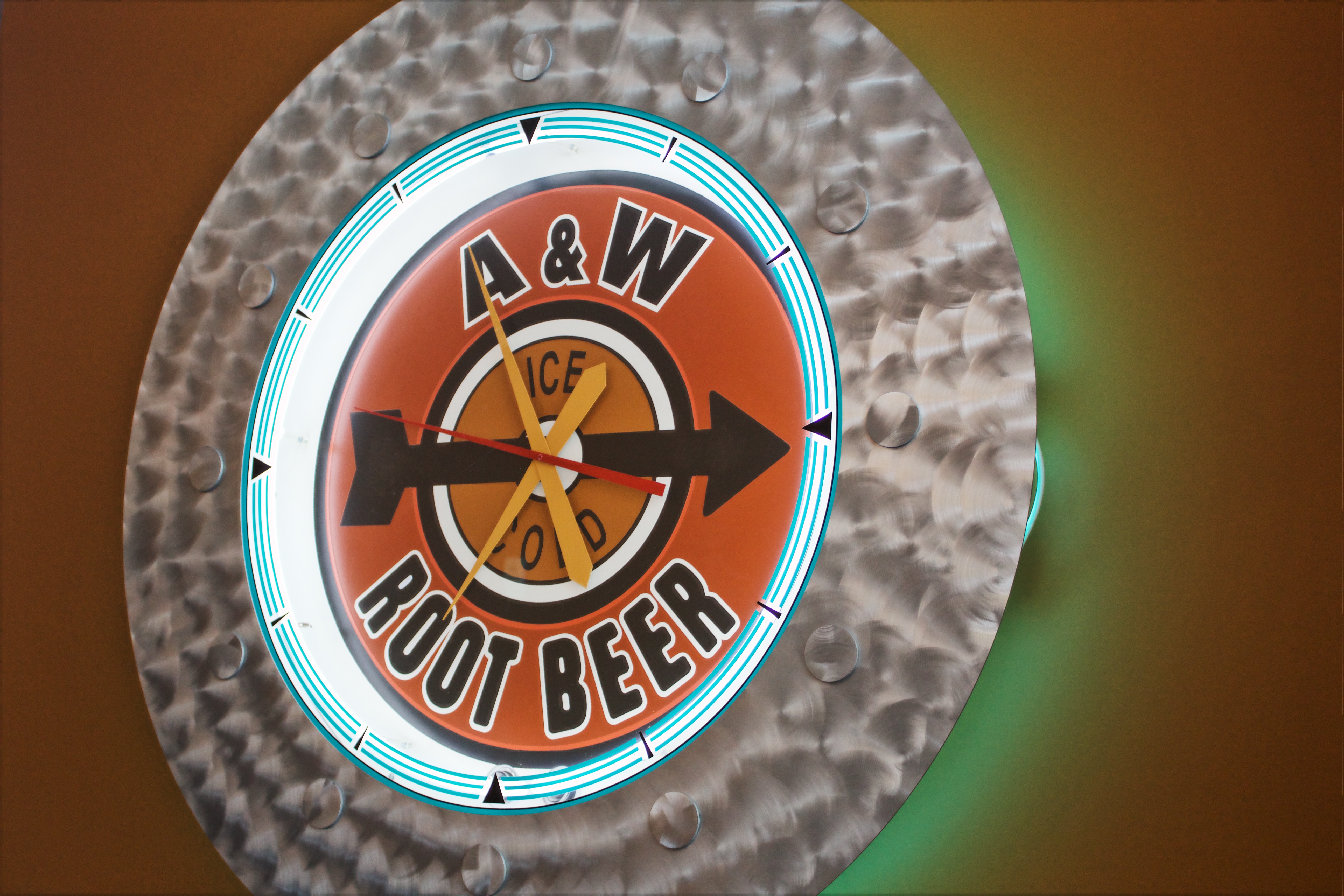 Round clock that reads 'A&W Root Beer' on an orange wall