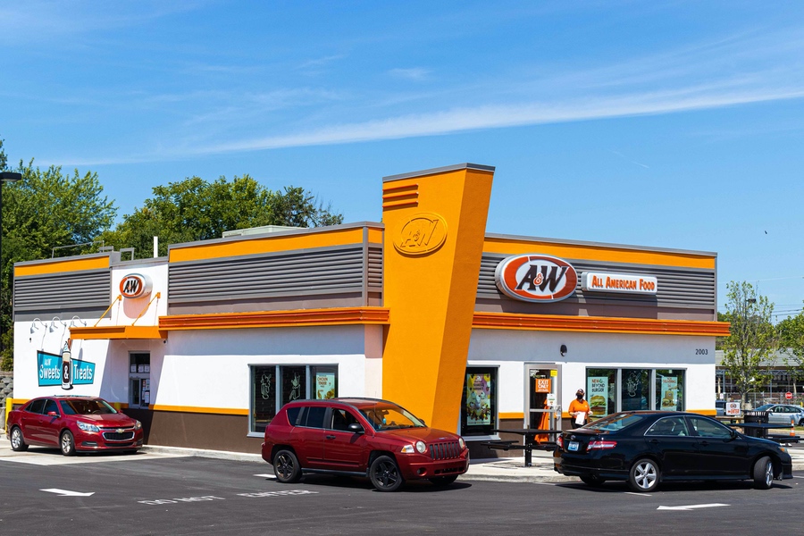 Exterior of A&W Restaurant in Richmond, Kentucky. Three cars are in the drive-thru. Team member is walking to a car holding an A&W to-go bag.