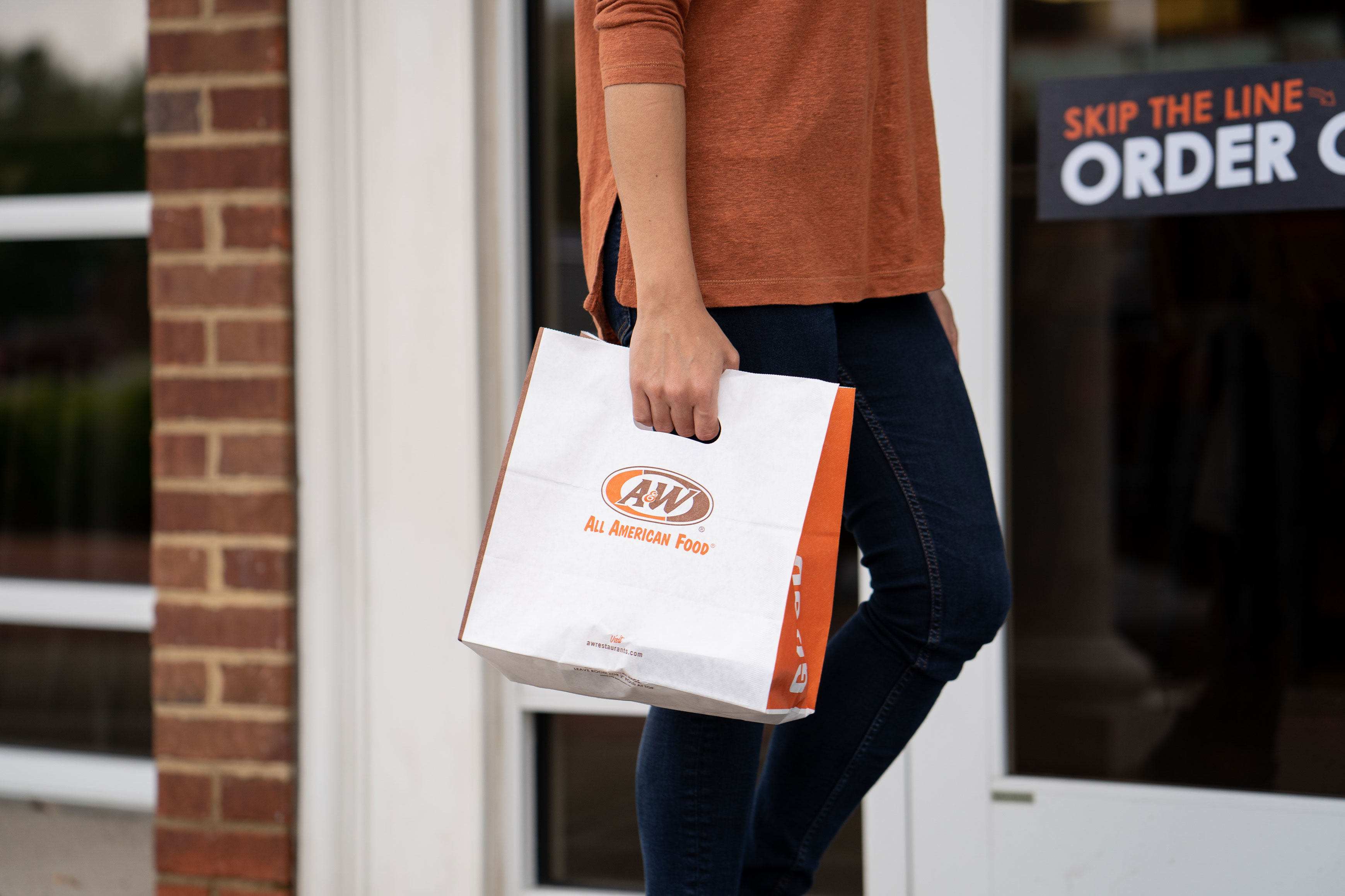Person carrying an A&W to-go bag.