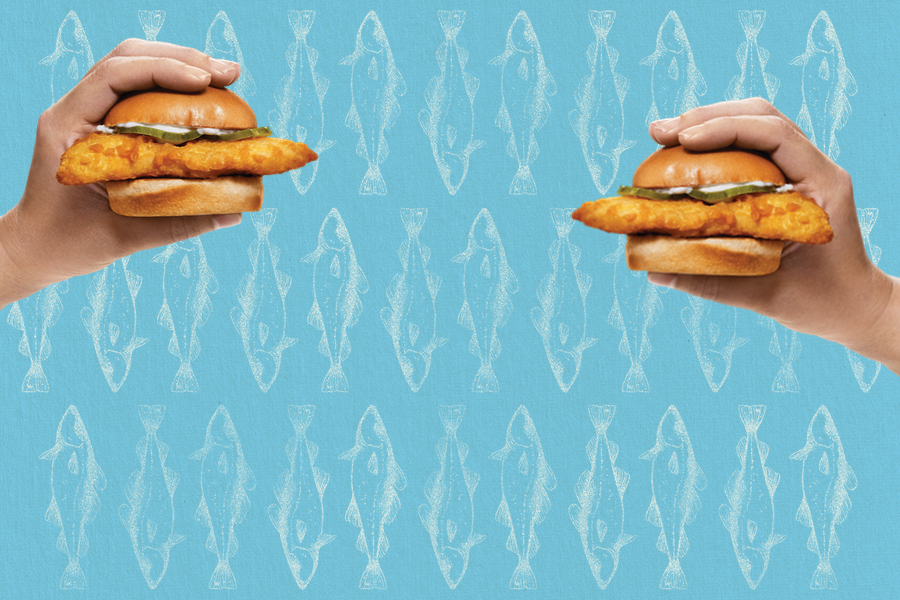 Background is blue with drawings of fish. Person holding Cod Slider in their hand on the right side of image.
