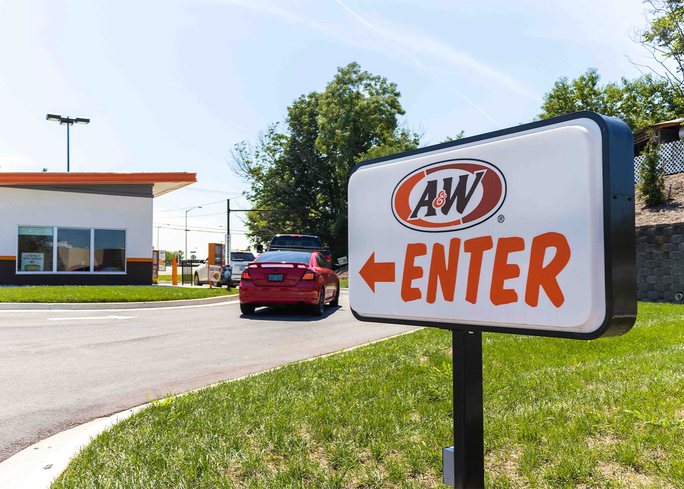 Exterior of A&W Restaurant in Richmond, Kentucky. Cars in drive-thru are out of focus with a sign that says 