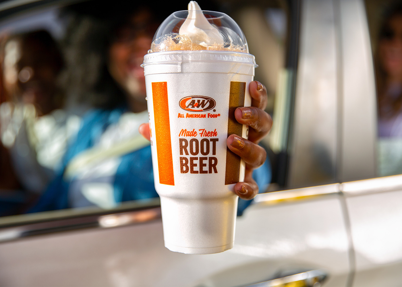 Person in car holding Root Beer Float in large A&W to-go cup
