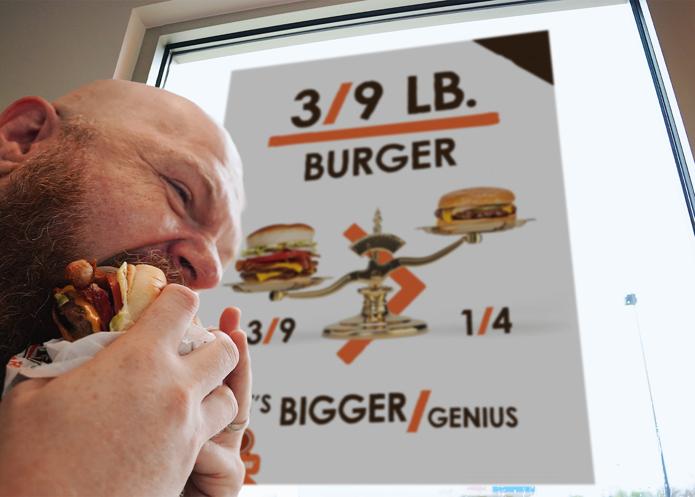 Photo of a man eating a burger inside an A&W Restaurant. A poster is behind him that reads 