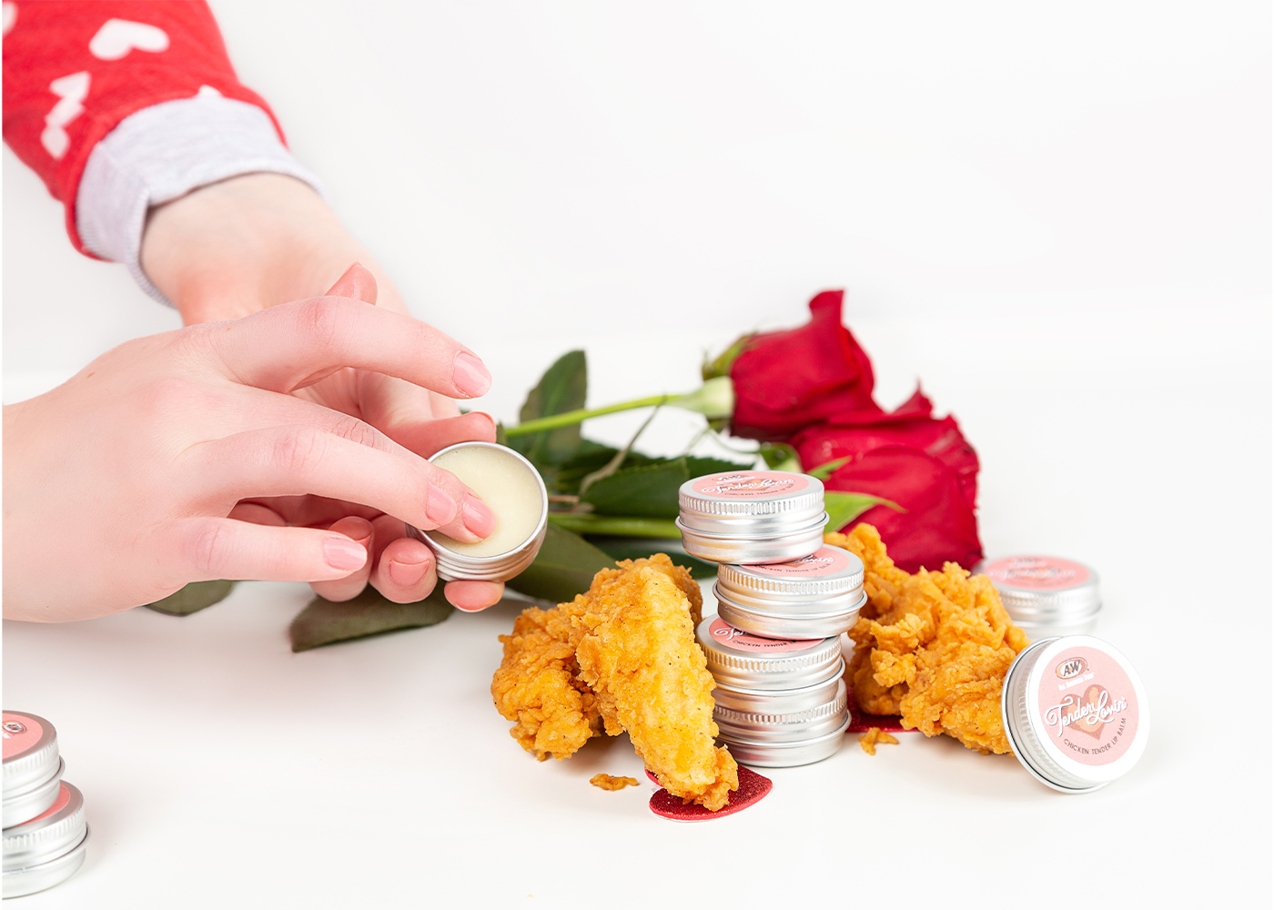 Hand holding tin of Tender Lovin' Lip Balm. Roses and A&W Chicken Tenders are in the background.